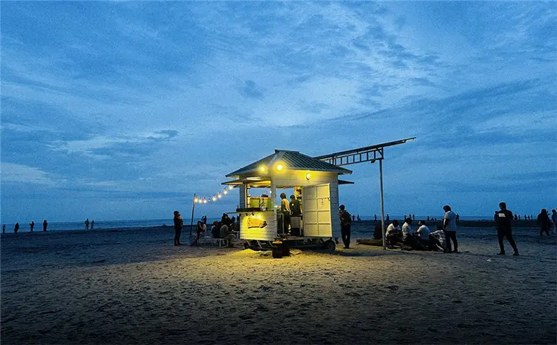 An illuminated beachside building beneath a blue evening sky