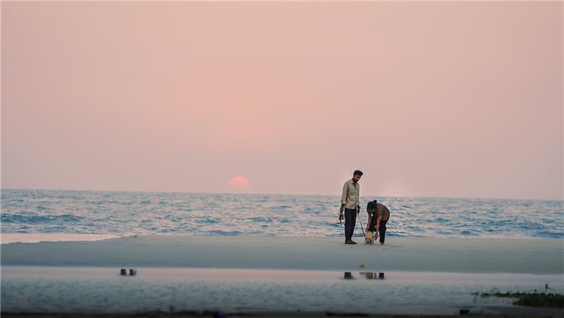 Two people beside the sea at sunset