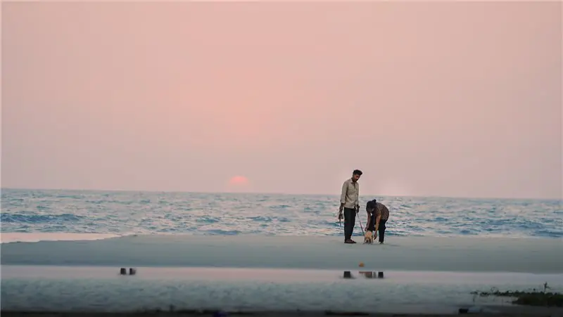 Two people together beside the sea at sunset