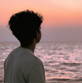 A person looking out at the sea at sunset