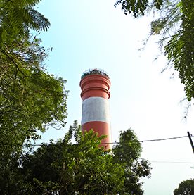 A red and white lighthouse seen through trees