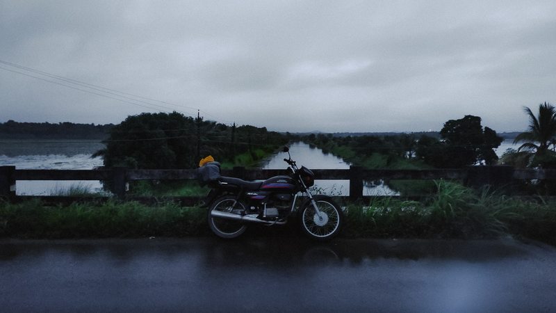 A motorcycle parked beside water beneath a dusky blue-gray sky