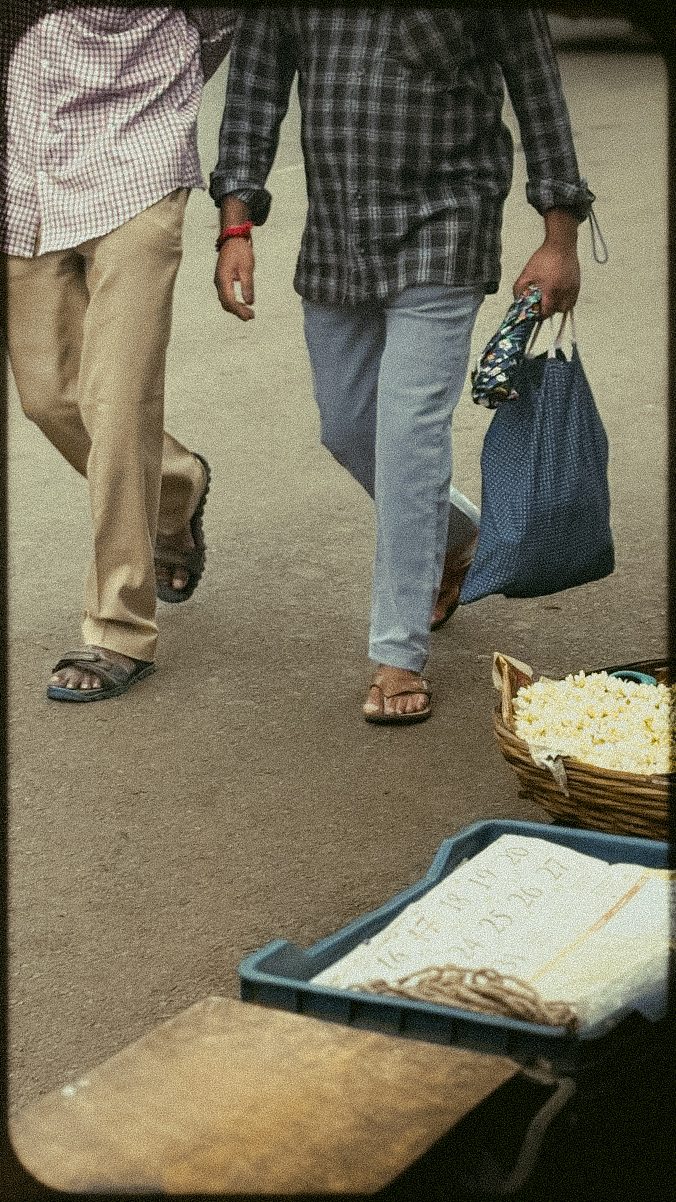 People walking past a street stall with a large basket of pale snacks