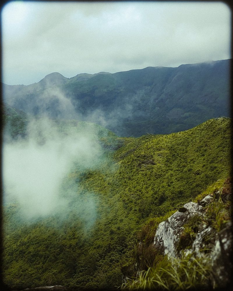 Cloud and mist moving across a rocky green mountain slope