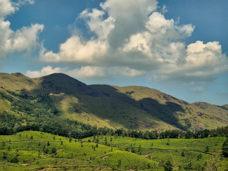 Green mountain slopes beneath large sunlit clouds