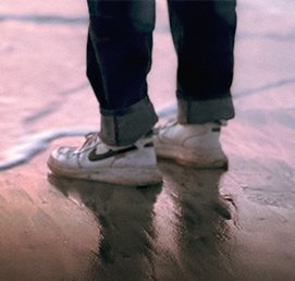 Shoes reflected in wet sand at the shoreline