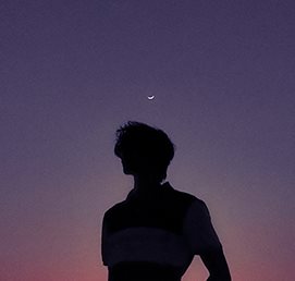 A person silhouetted under a crescent moon