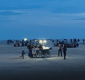 People gathered around a cart on a beach at blue hour