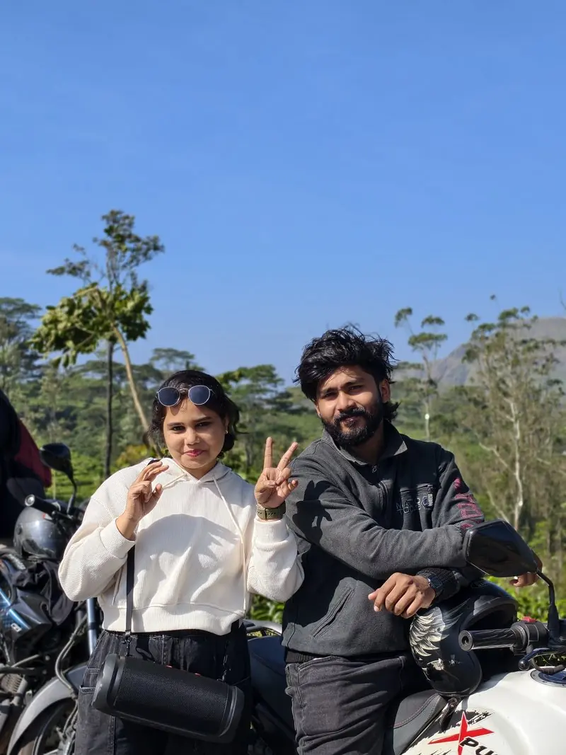 Two people posing beside motorcycles under a blue sky