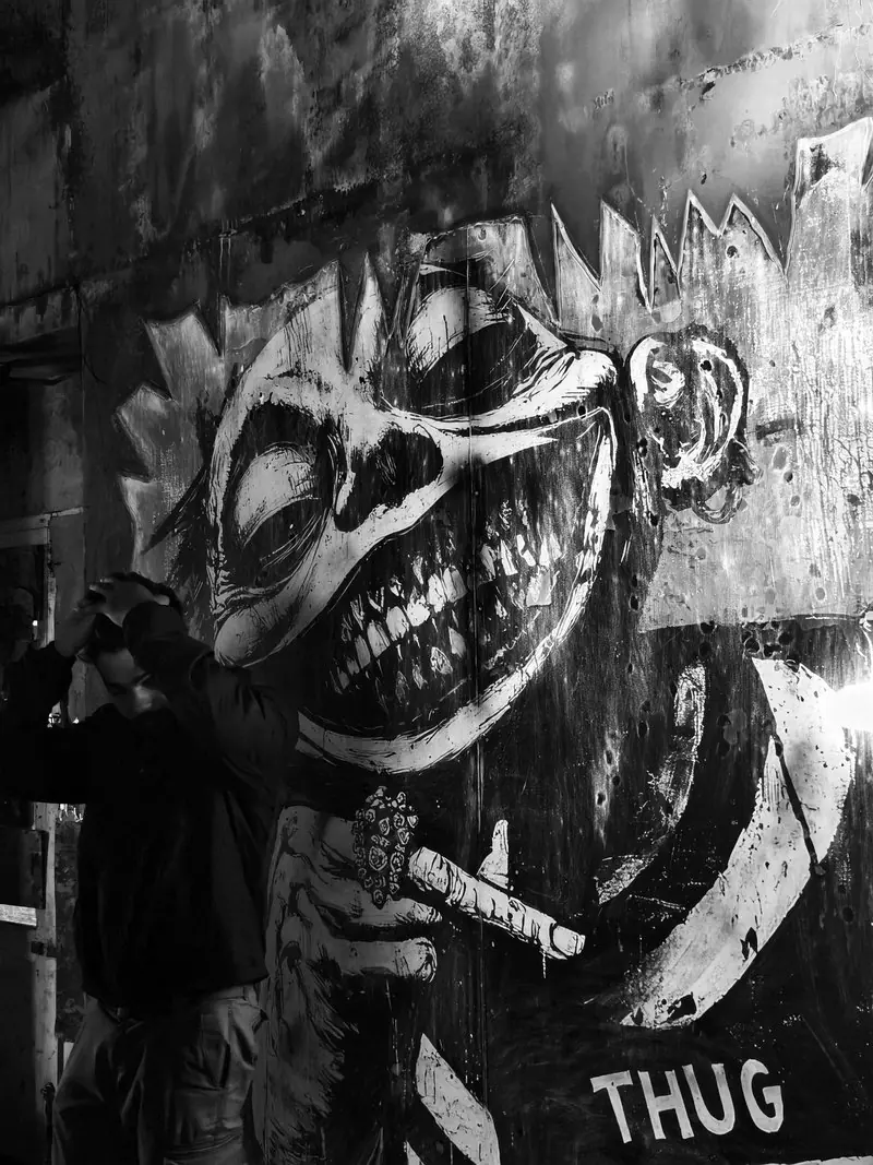 A painted face on a weathered wall in black and white