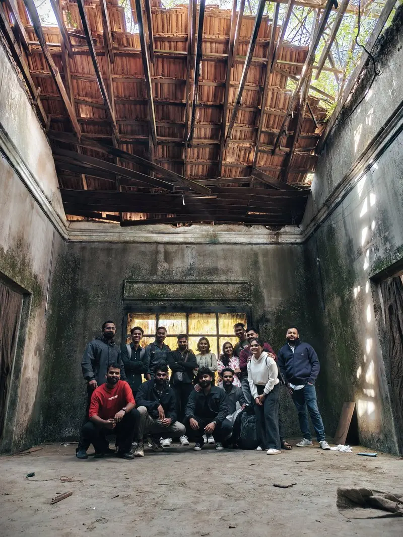 A group gathered inside a building beneath wooden roof beams