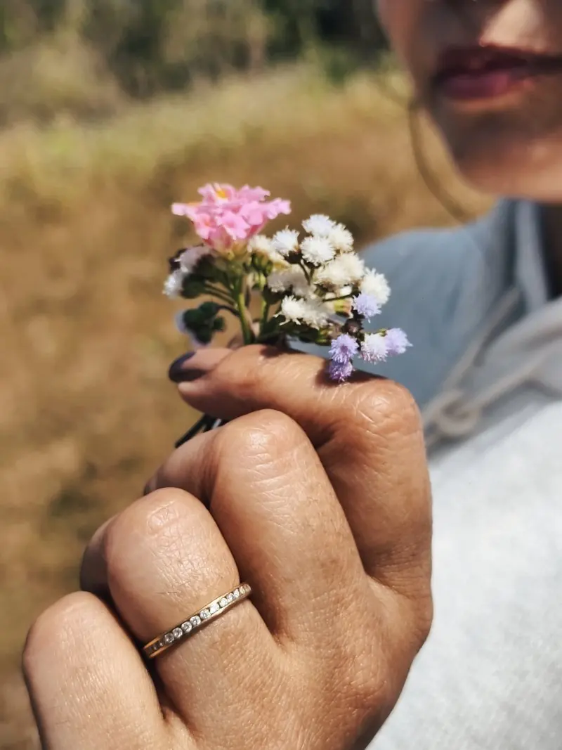 A hand holding a small cluster of colorful wildflowers