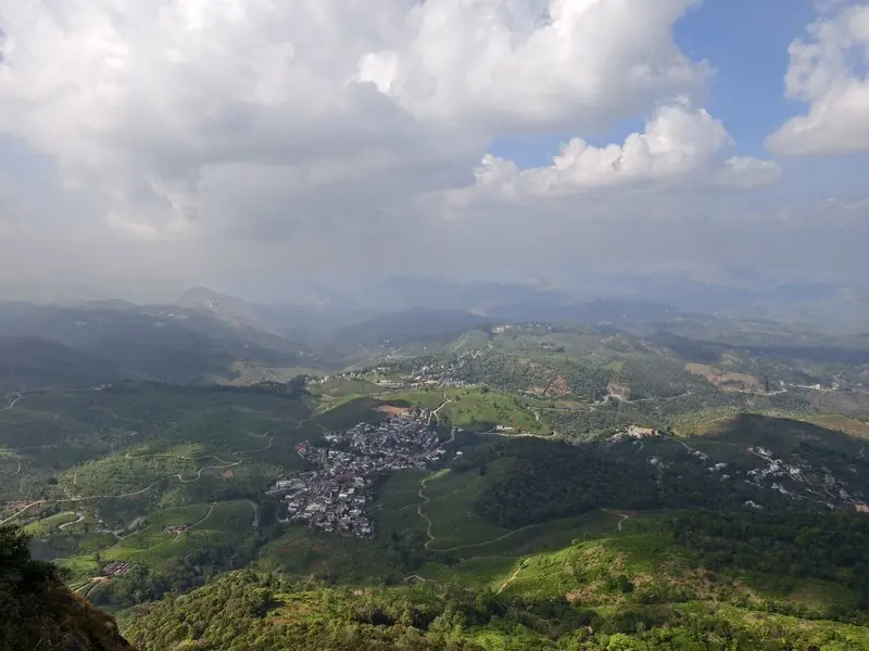 A green valley beneath bright clouds and distant mountain ridges