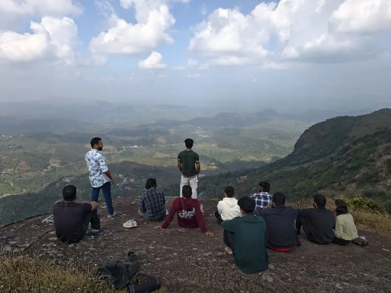 People resting on a rocky hilltop above a broad valley