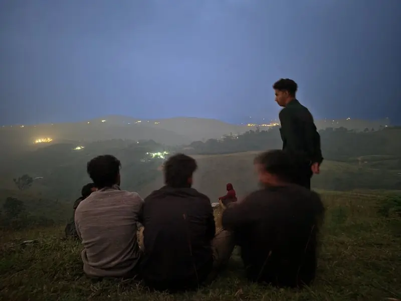 People sitting together above a valley at dusk