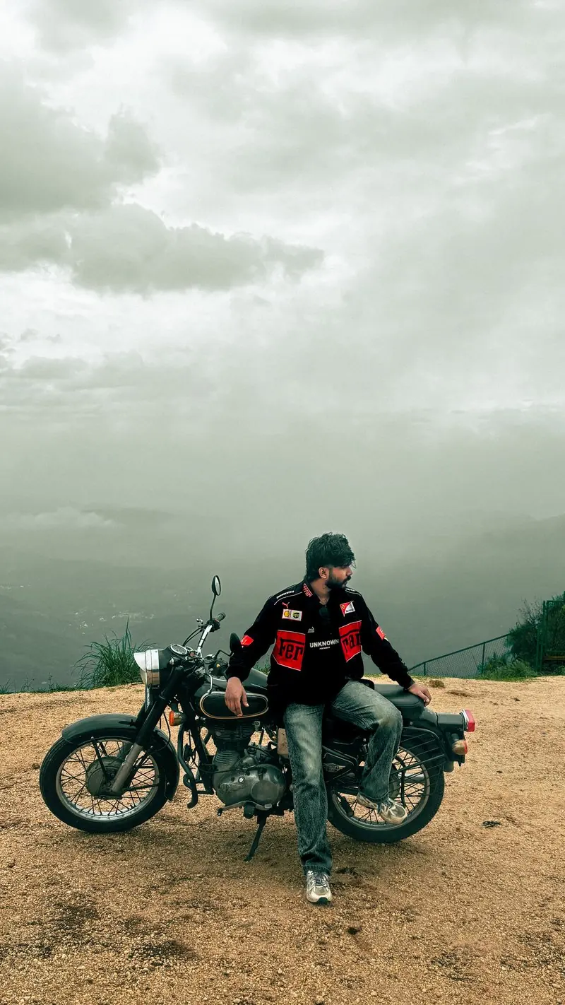 Two people beside motorcycles beneath a cloudy sky
